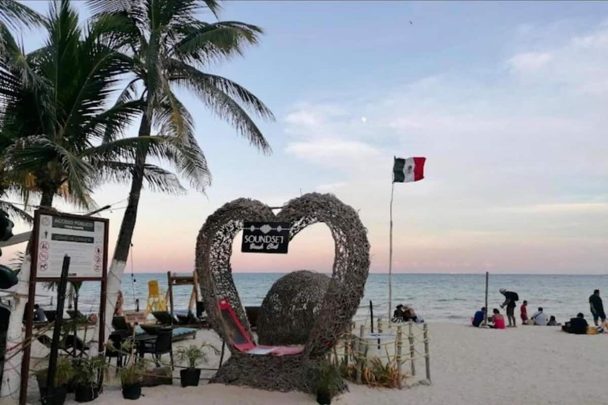 A beach with a heart-shaped structure, a flag, and a signboard.