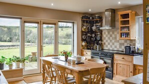 Una cocina con armarios de madera, estufa y comedor con sillas y mesa.