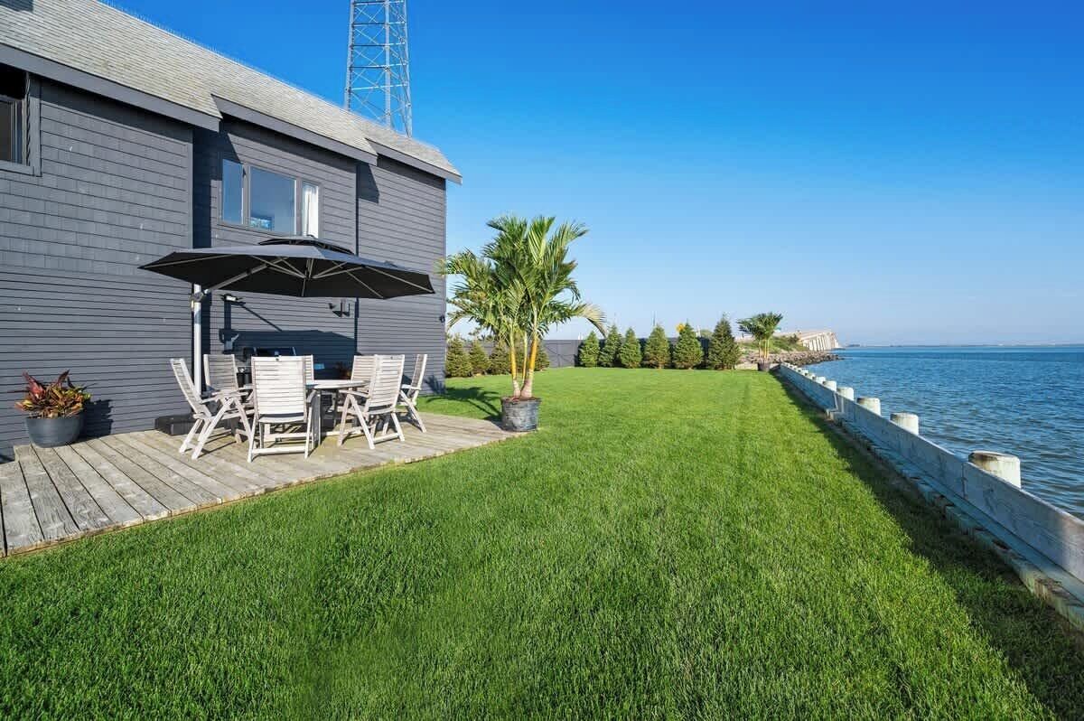 A house with a deck, outdoor furniture, and a view of the water.