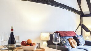 A dining area with a wooden table set for two, a bottle of wine, and a bowl of fruit. - 1 bedroom accommodation in Abingdon (Abingdon)