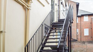 A narrow, black metal staircase with a handrail leading to a building entrance. - 1 bedroom accommodation in Abingdon (Abingdon)