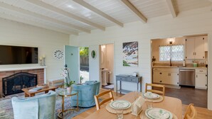 Ein geräumiges Wohnzimmer mit Kamin, eine Essecke mit Holztisch für vier Personen und eine Küche mit modernen Geräten.