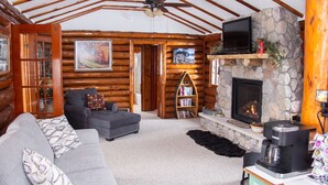 A log cabin interior with a fireplace, a sofa, a bookshelf, and a coffee maker.