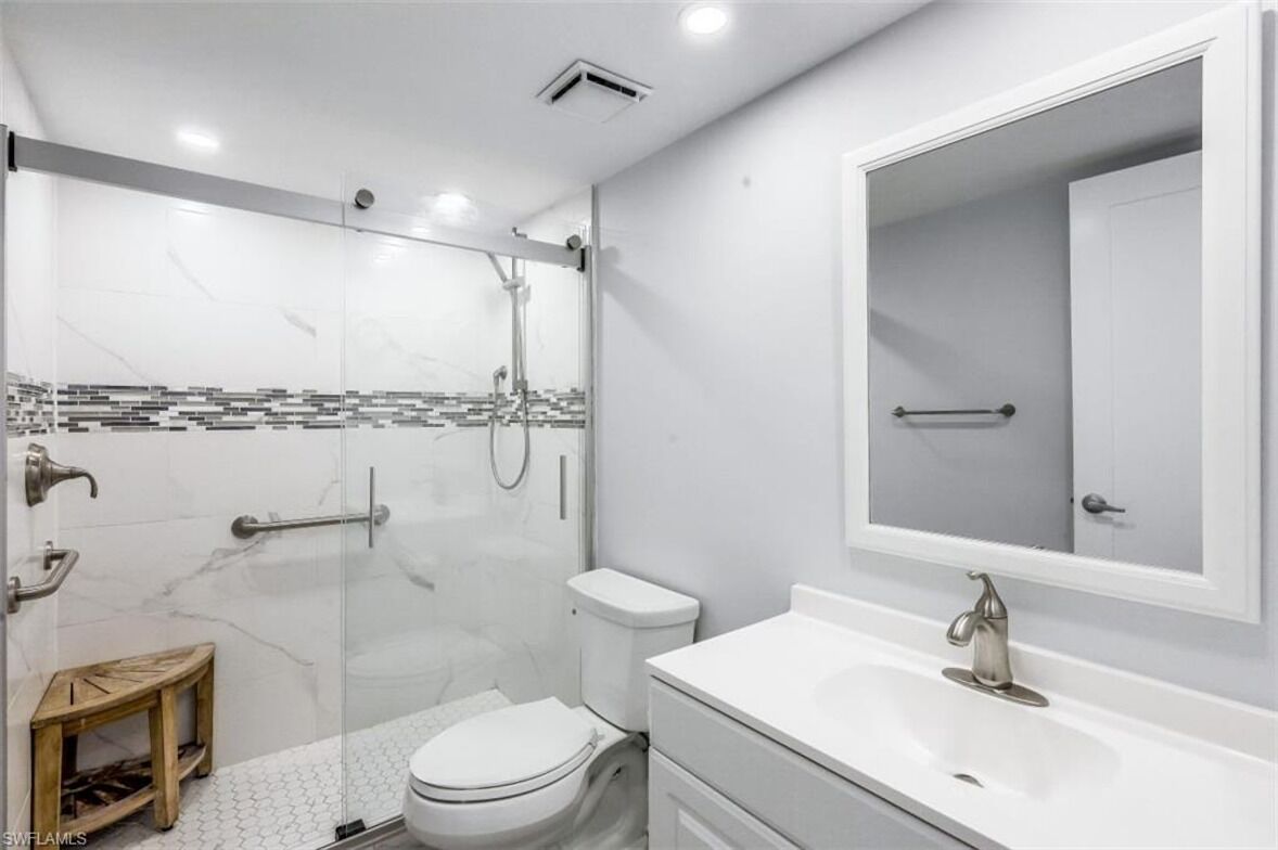 Une salle de bain moderne avec une douche à parois de verre, des toilettes, un lavabo et un miroir.