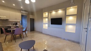 Una cocina moderna con zona de comedor, televisor de pantalla plana montado en la pared e iluminación empotrada.