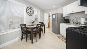 A modern kitchen with white cabinets, a stainless steel refrigerator, and a gas stove. - Modern North End Studio (Boston)