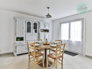 A dining area with a round table, six wooden chairs, and white cabinetry with glass doors.