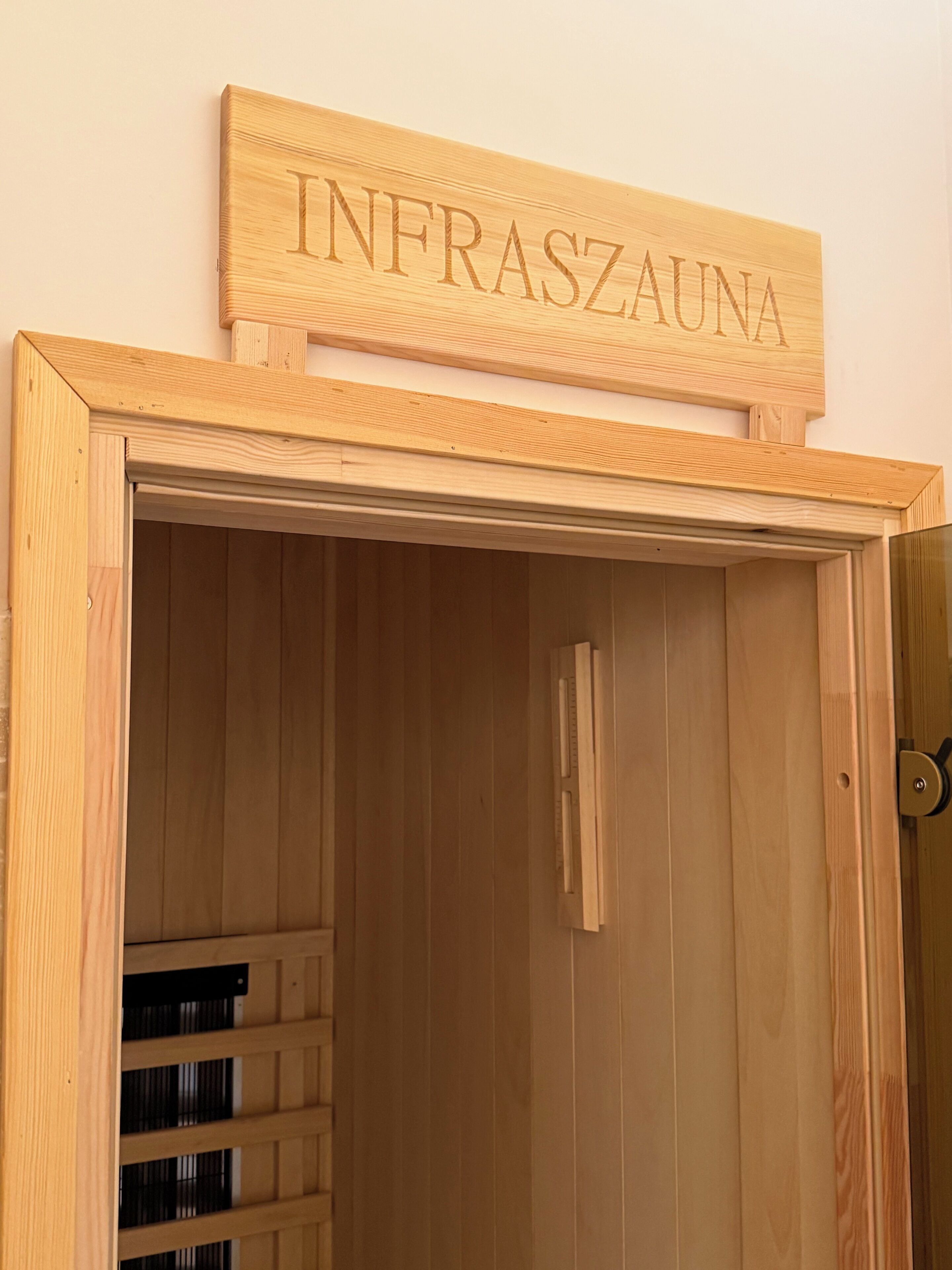 A wooden door with the inscription "INFRASZAUNA" above it.