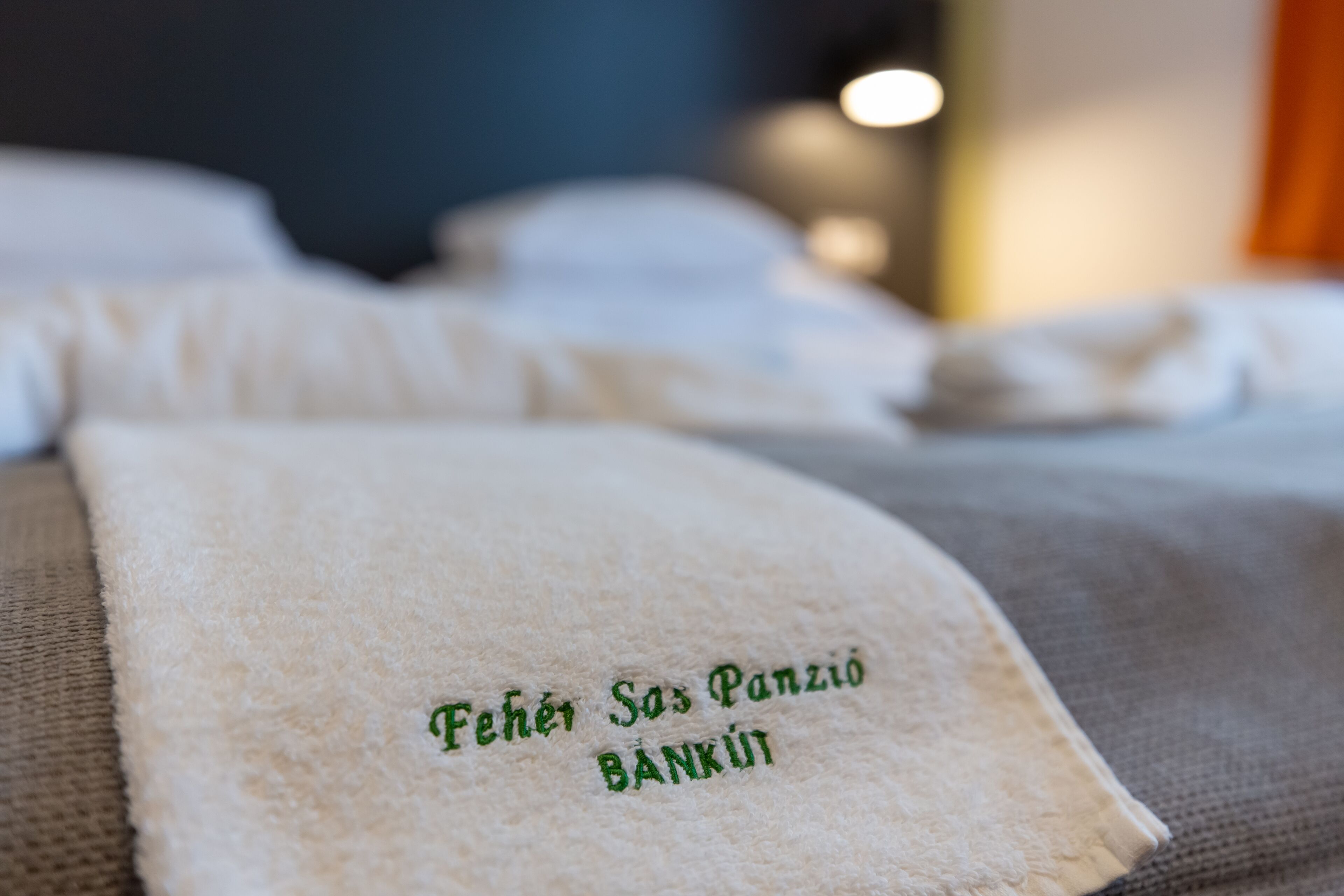 Una toalla doblada con texto bordado sobre una cama.