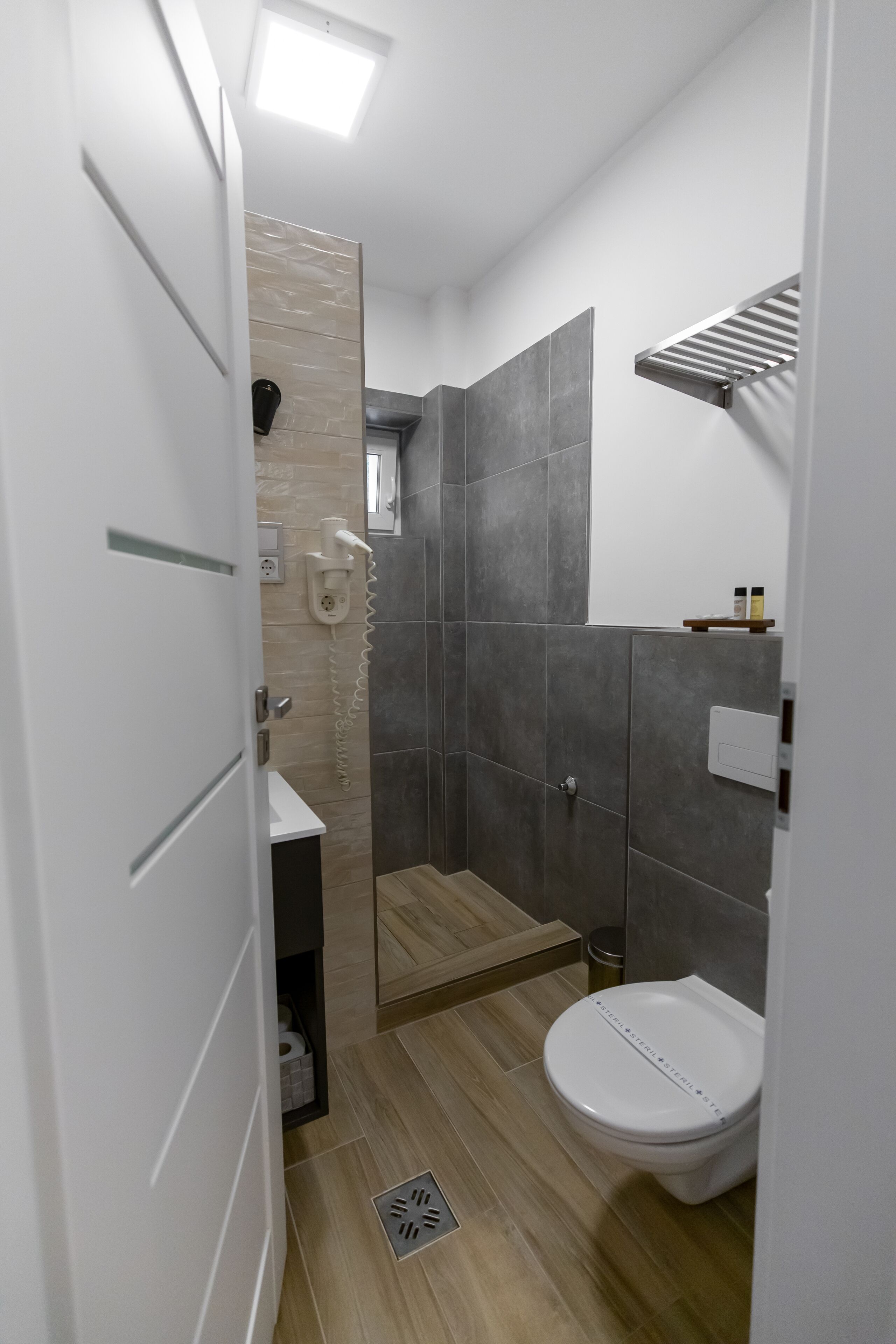 A modern bathroom with a shower, toilet, and a small sink area.