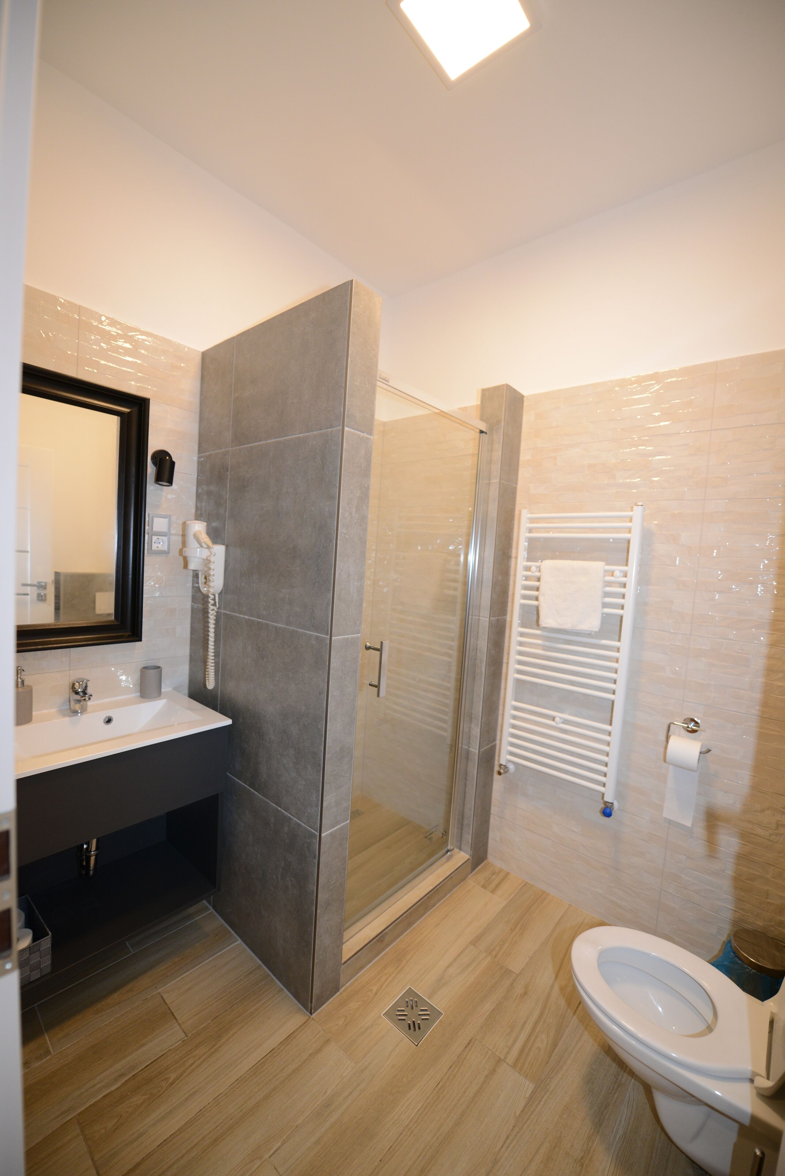 A modern bathroom with a shower, toilet, sink, and a towel rack.