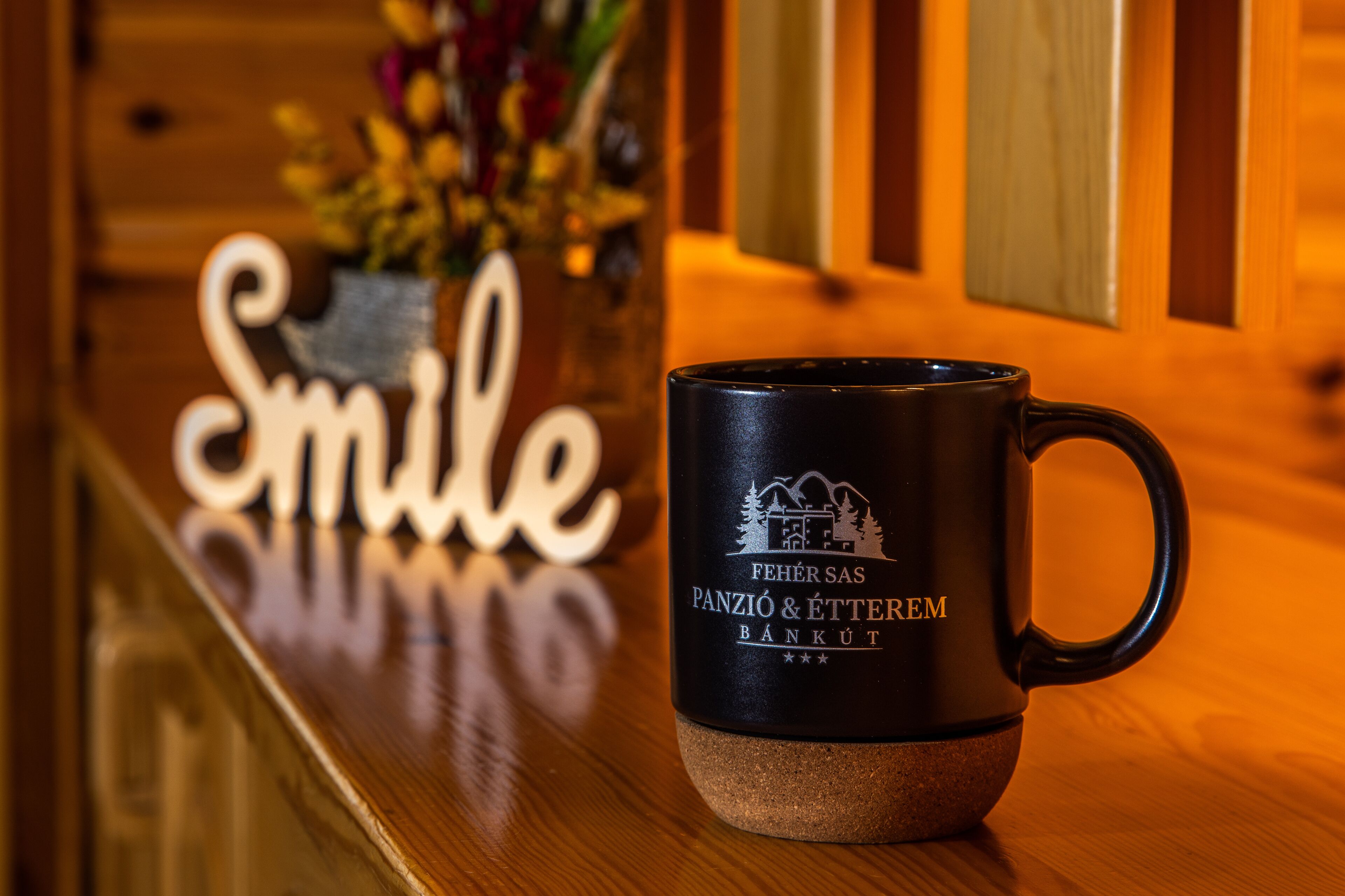 A black mug with a logo on a wooden surface.