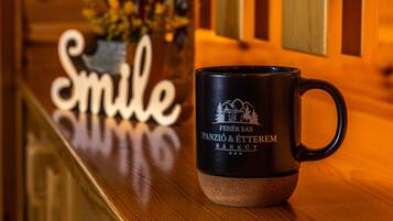 A black mug with a logo on a wooden surface.