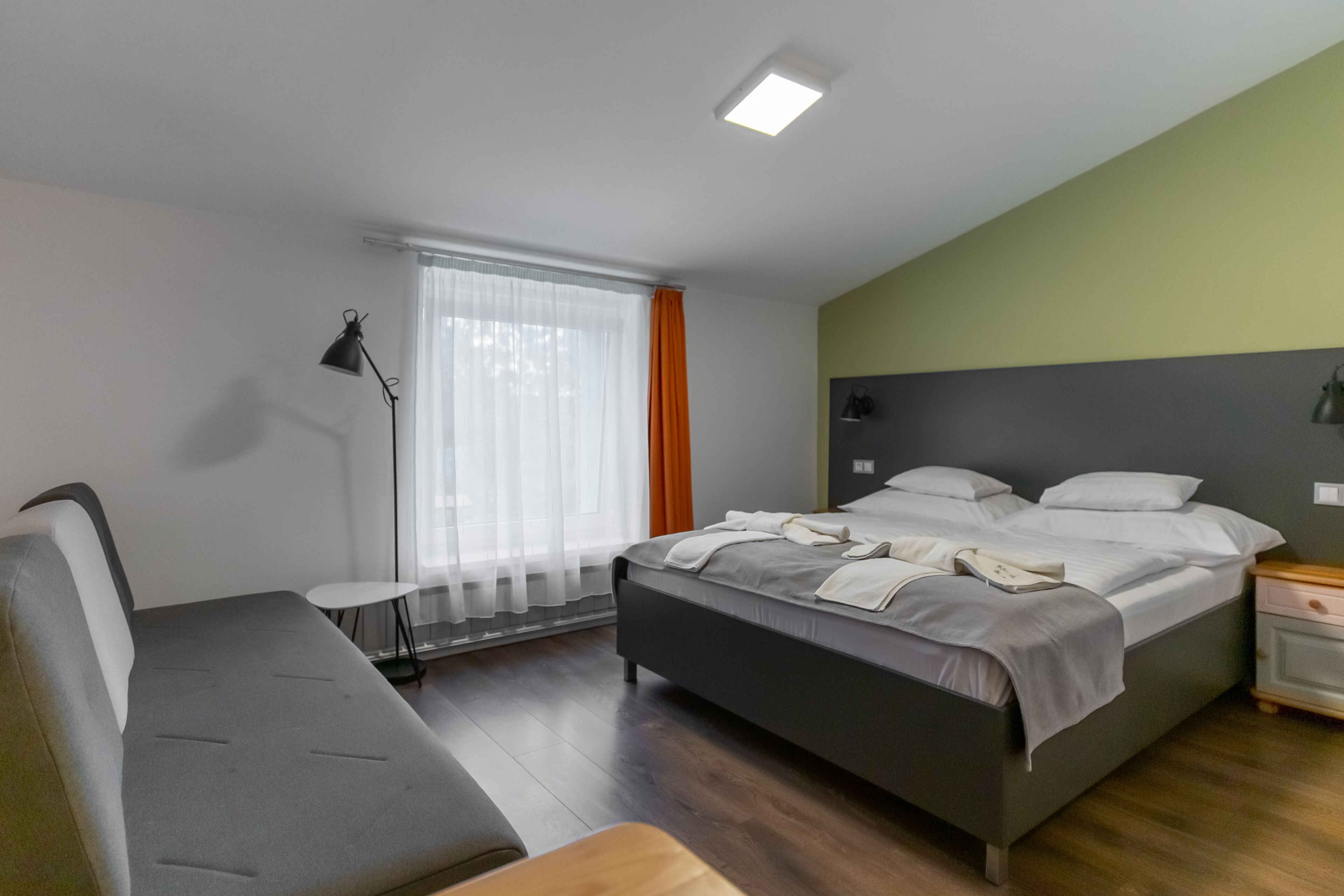 Un dormitorio moderno con cama, mesita de noche, lámpara y una pequeña mesa.