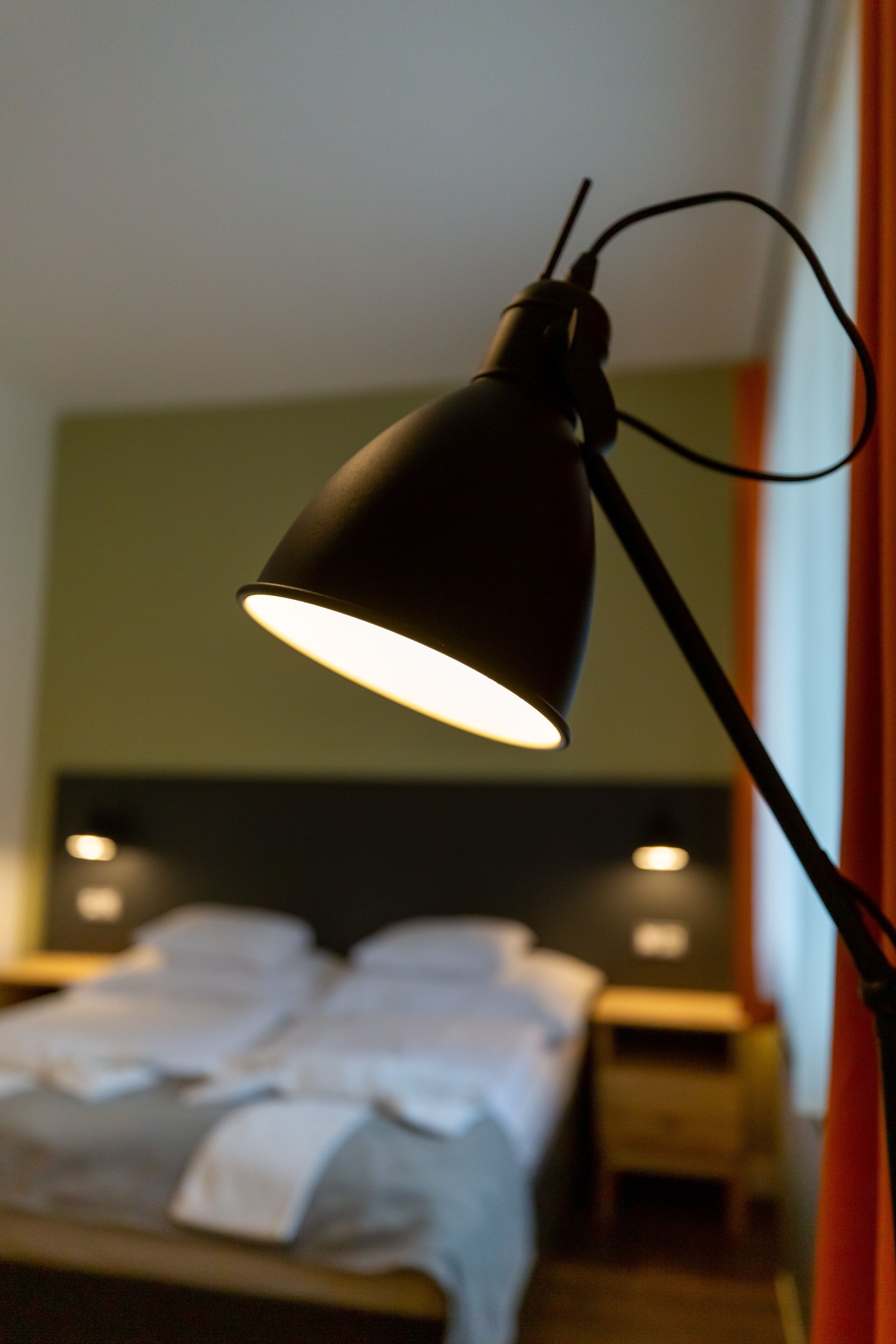 A room with a bed, a bedside table, and a lamp.