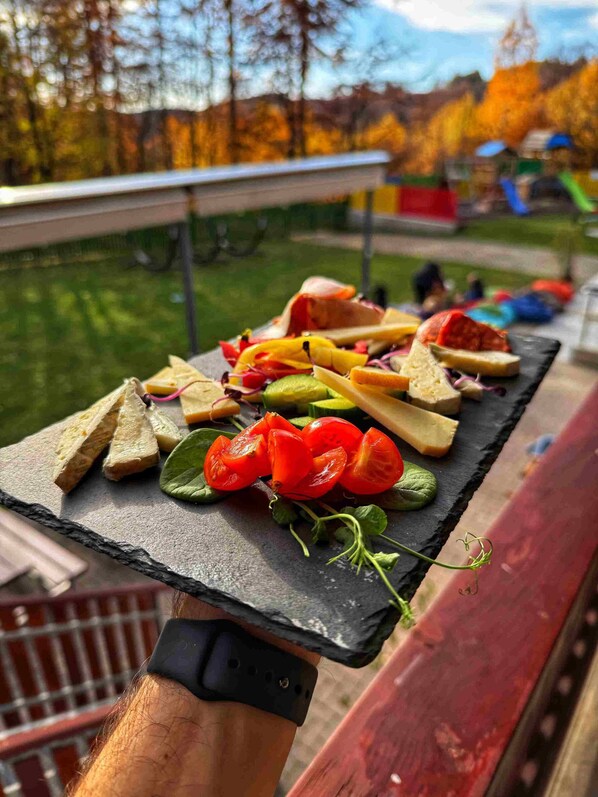 A charcuterie board with various cheeses, meats, and vegetables on a slate board.