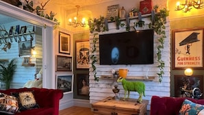 A cozy living room with a fireplace, a television mounted on the wall, and a red sofa. - James' Place @ The Park (Merthyr Tydfil)