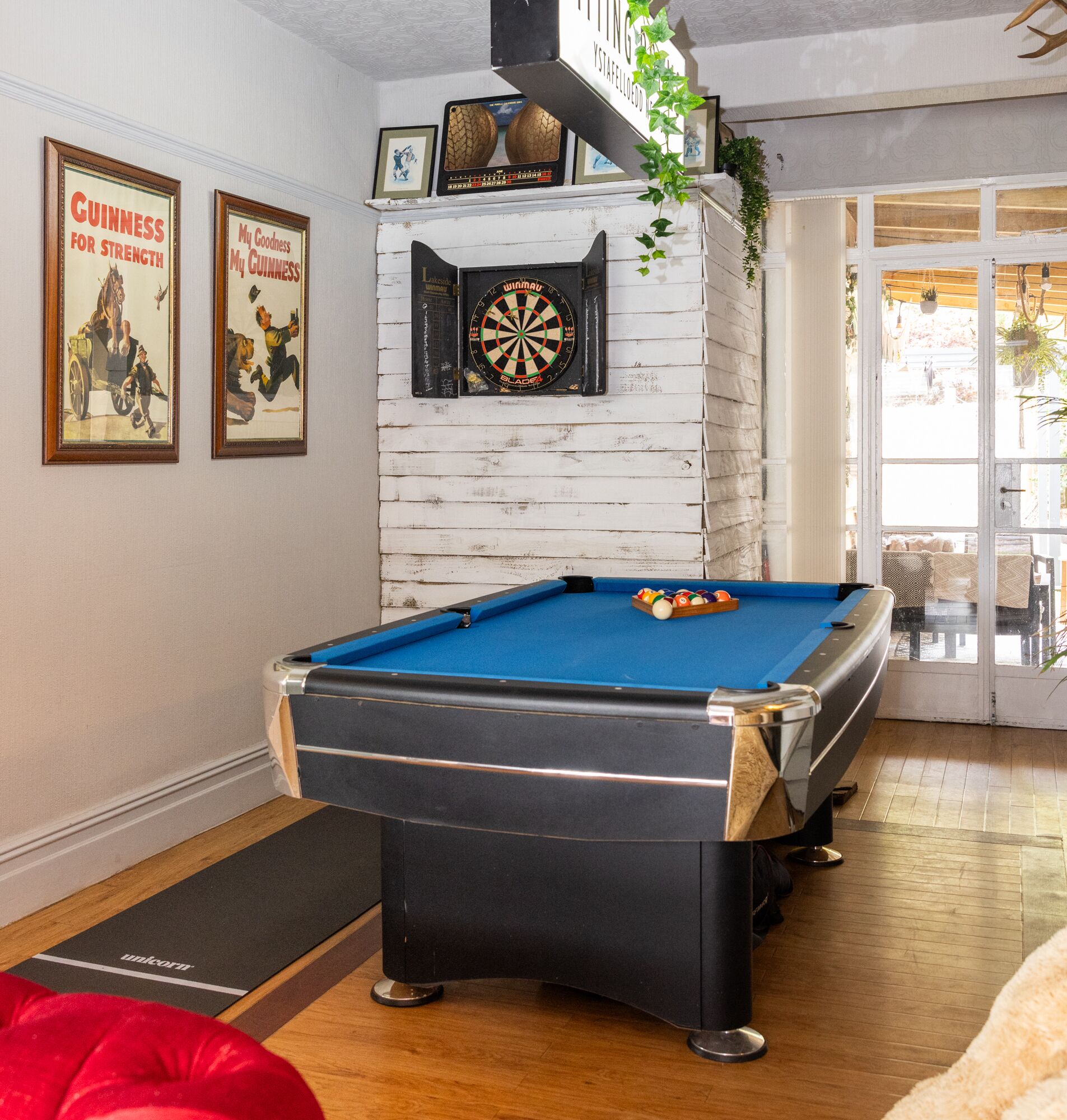 A pool table with a dartboard and framed Guinness advertisements.