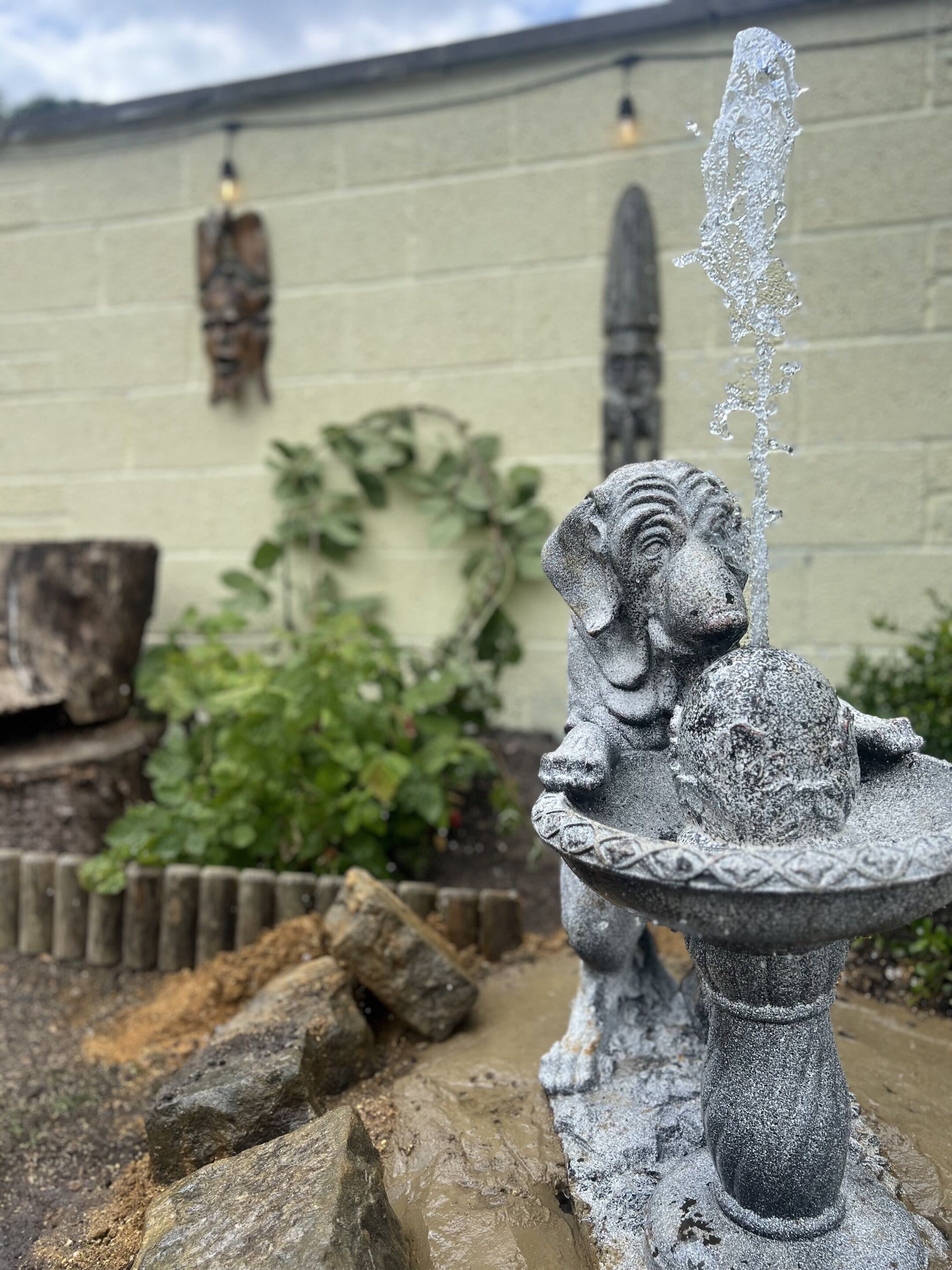 Una fuente de piedra con estatua de león en un jardín.