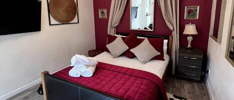 Un dormitorio con cama, candelabro, espejo, mesita de noche y alfombra.