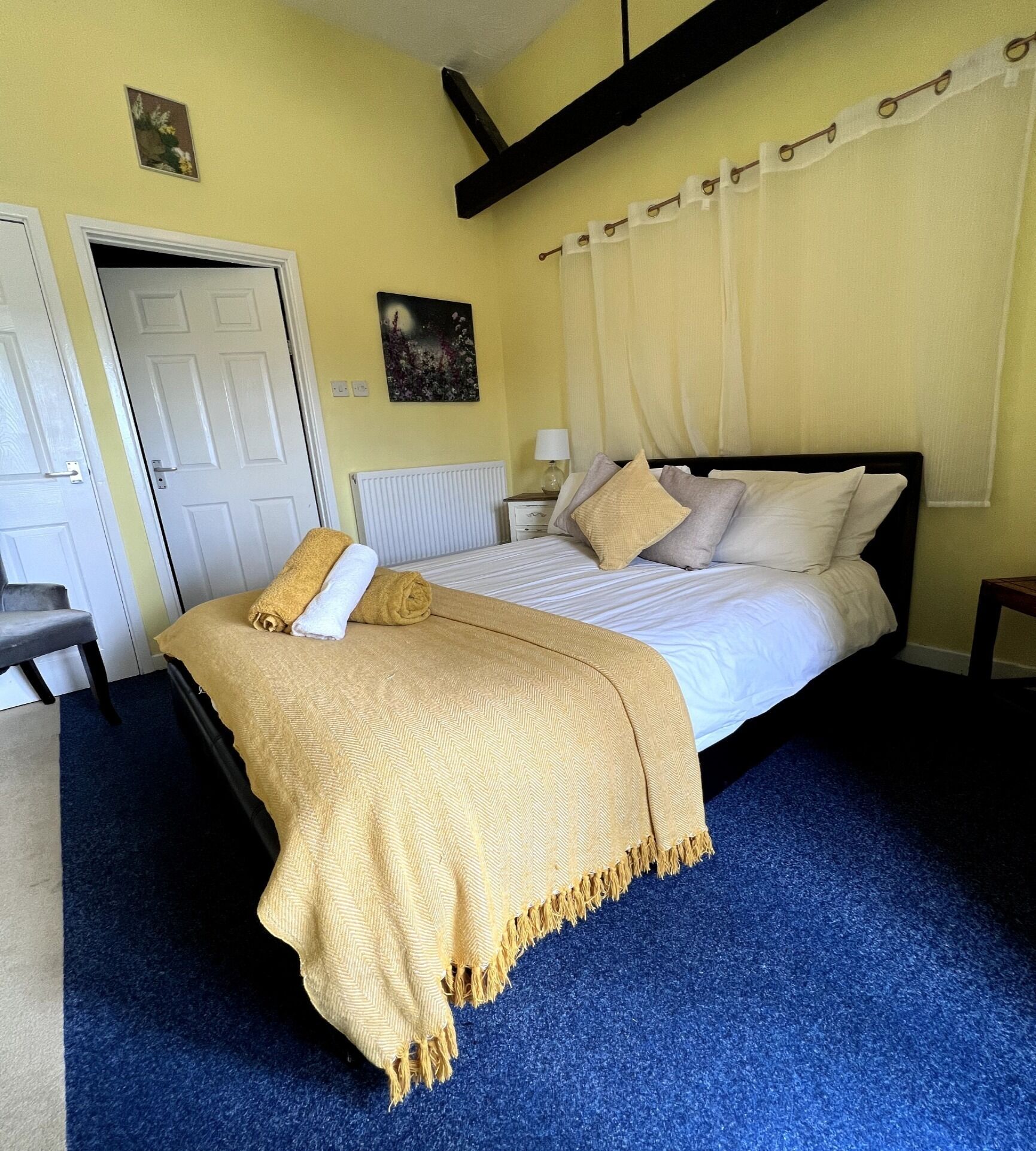 A bedroom with a bed, a chair, a radiator, and a door.