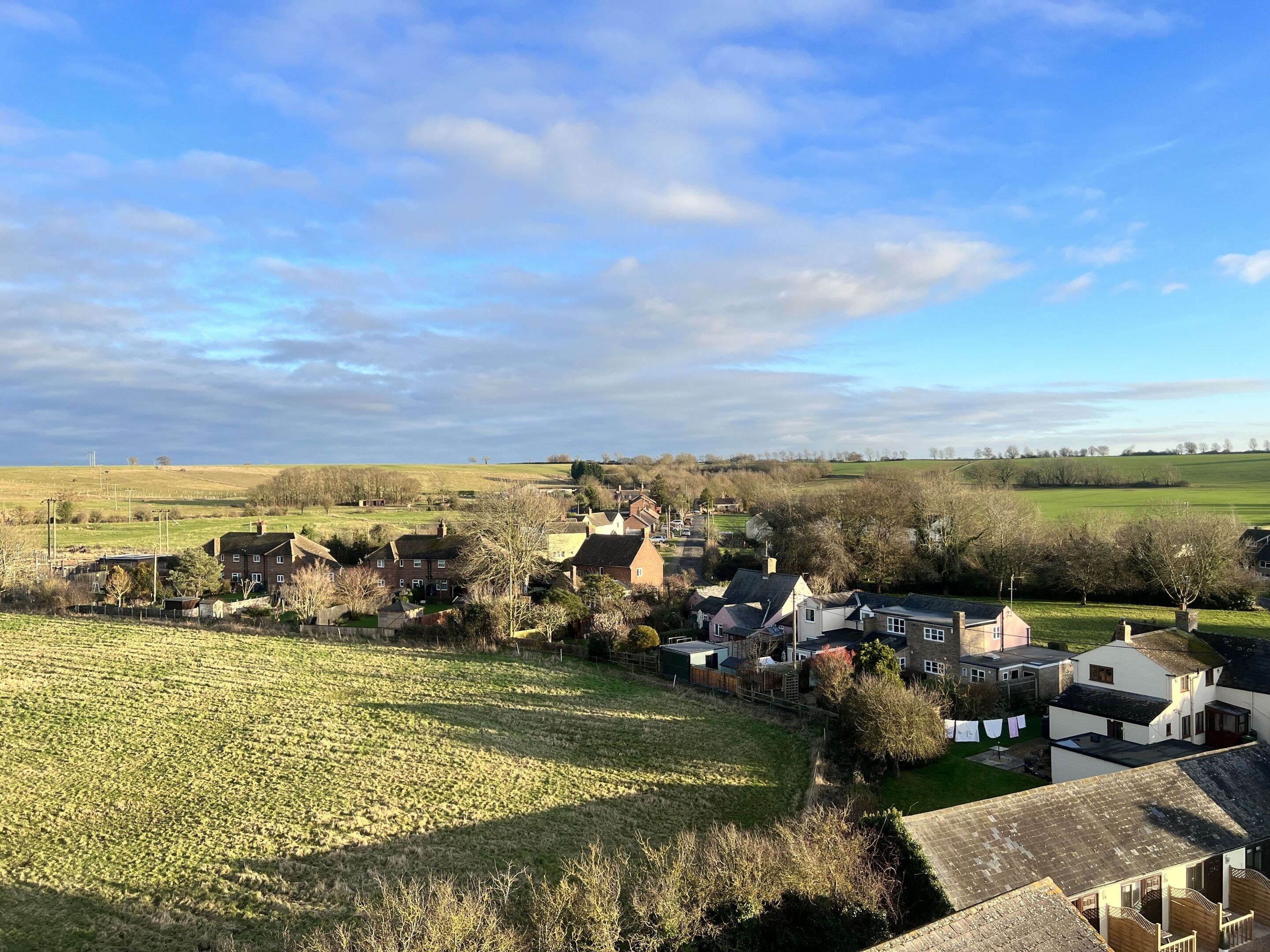 A rural village with houses, fields, and a clear sky.