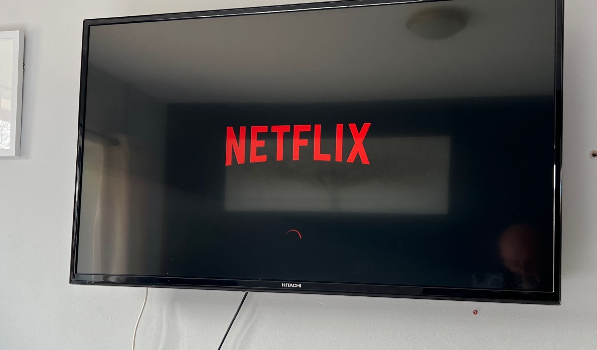 Ein Flachbildfernseher an der Wand mit dem Wort 'NETFLIX' in roten Buchstaben.