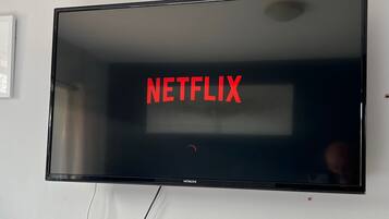 Ein Flachbildfernseher an der Wand mit dem Wort 'NETFLIX' in roten Buchstaben.