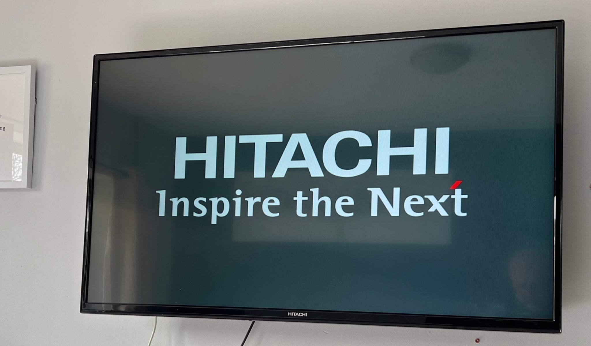 HITACHI-merkkinen näyttö, jonka tunnuslause on: ”Innosta seuraava sukupolvi”.