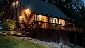 A log cabin with a porch and a staircase leading to the entrance.