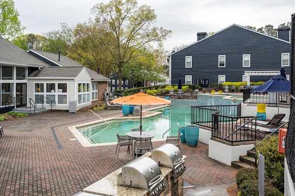Relax by the pool surrounded by a patio, barbecue grills, and comfortable outdoor furniture.