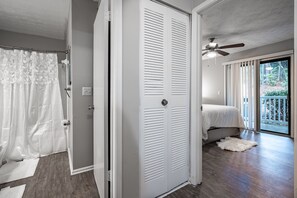 Relax in this serene bedroom with a large bed, ceiling fan, and expansive views through glass doors to the outdoors.