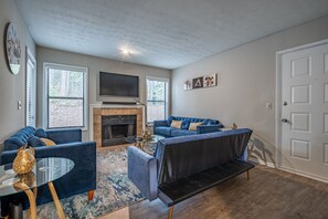 Relax in this cozy space with a large flat-screen TV, comfortable sofa, and a fireplace.