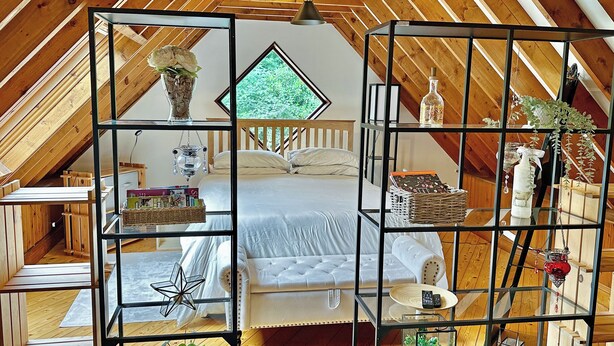 Acogedor dormitorio en ático con cama, estanterías y vistas al exterior.