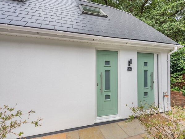 A white building with two green doors and a small window on the roof.