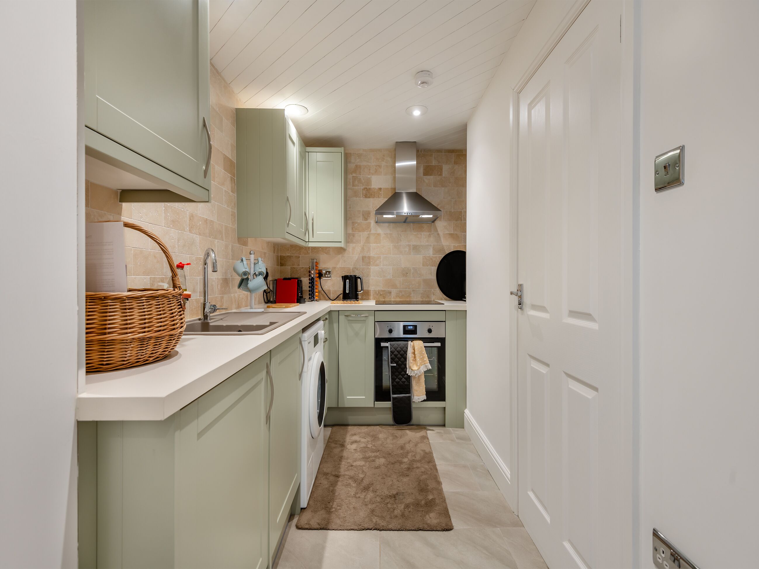 A compact kitchen with a washing machine, a coffee maker, and a stove.
