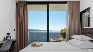 A hotel room with a bed, a desk, and a view of the sea. - Villa Sea Breeze, 5 bedroom Luxury Villa near the sea, private heated pool, Omiš Brzet (Omiš)