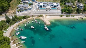 An aerial view of a coastal property with modern buildings, a marina with several boats, and a clear turquoise sea. - Villa Sea Breeze, 5 bedroom Luxury Villa near the sea, private heated pool, Omiš Brzet (Omiš)