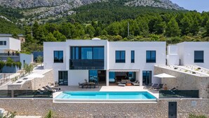 A modern two-story house with a swimming pool, stone walls, and a view of a mountainous landscape. - Villa Sea Breeze, 5 bedroom Luxury Villa near the sea, private heated pool, Omiš Brzet (Omiš)