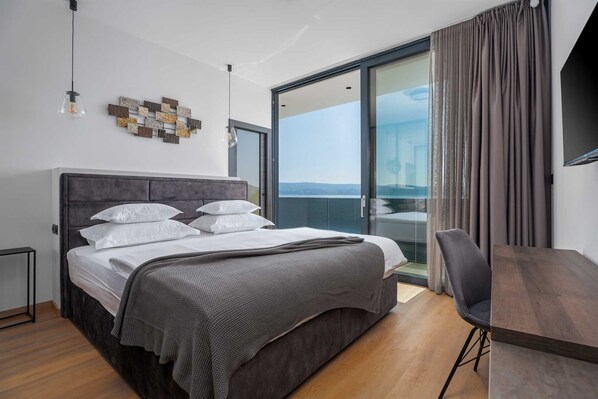 Un dormitorio moderno con una cama grande, un escritorio y vistas al exterior.