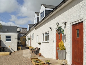 A narrow street with white houses, a wooden bench, and a small garden area.