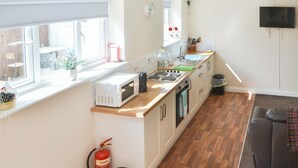 Eine kleine Küche mit Mikrowelle, Herd, Spüle und Feuerlöscher.