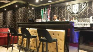 A bar area with a counter, stools, and a barista behind the counter.