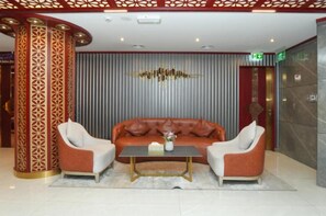 A lobby with a sofa set, two armchairs, a coffee table, and a decorative wall with vertical lines. - Concorde Palace Hotel (Dubai)