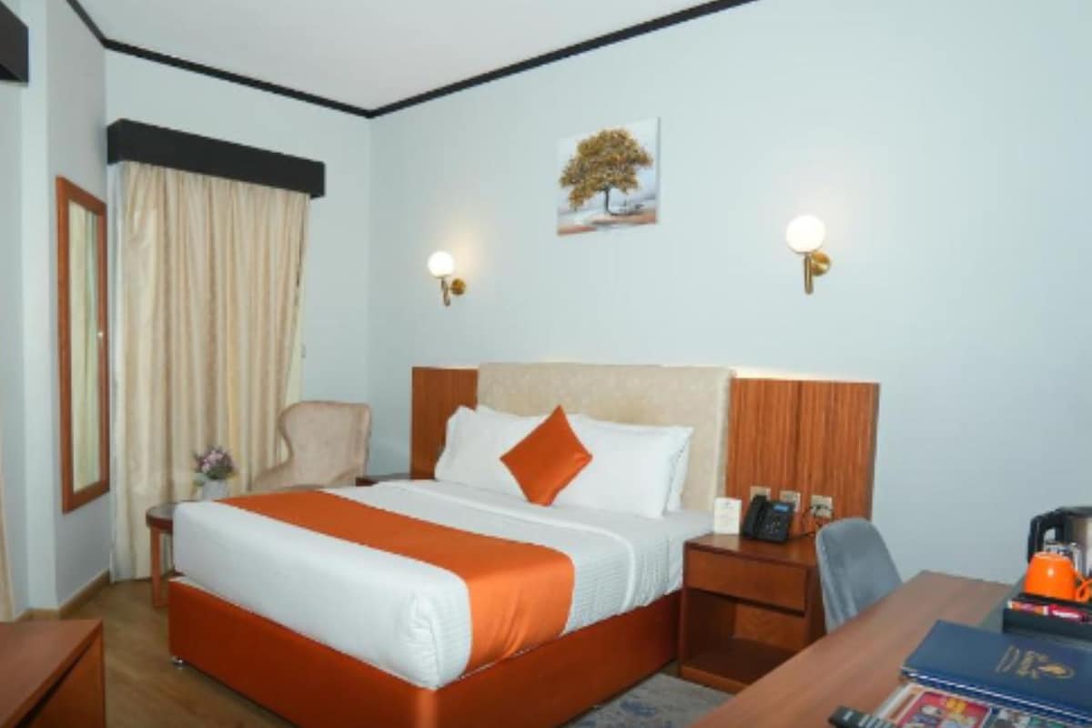 A hotel room with a bed, bedside tables, a desk, and a chair.