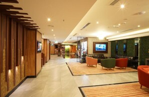 A hotel lobby with a reception desk, seating area, and a television screen. - Concorde Palace Hotel (Dubai)