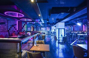 A bar area with tables and chairs, a counter, and a neon-lit ceiling. - Concorde Palace Hotel (Dubai)