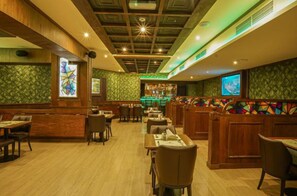 A restaurant interior with wooden paneling, a bar area, and a green patterned wall. - Concorde Palace Hotel (Dubai)