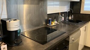 Eine moderne Küche mit schwarzem Arbeitsplatz, einem eingebauten Herd, einer Kaffeemaschine und einem Spülbecken.