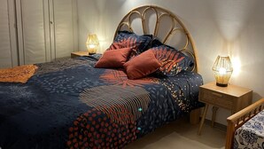 Ein Schlafzimmer mit einem Bett, zwei Nachttischen, einer Wandleuchte und einem Kleiderschrank.